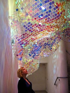 a woman looking up at a multicolored light fixture