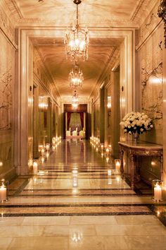 candles are lit on the floor in an elegant hallway with chandeliers and marble walls