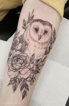 an owl and roses tattoo on the arm