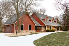 a large red house with two garages and lots of trees in the front yard