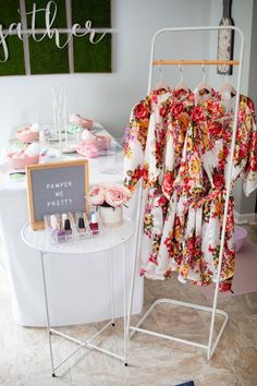 a dress hanging on a clothes rack next to a table with cosmetics and other items