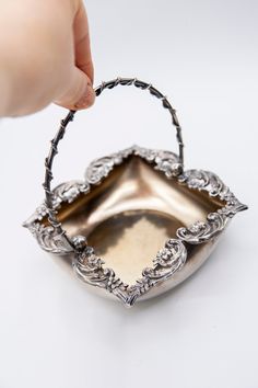 a hand holding a silver basket with handles