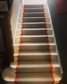 a set of stairs with orange tape on the bottom and bottom, leading up to an upstairs hallway