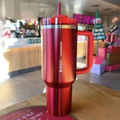 a red coffee cup sitting on top of a wooden table