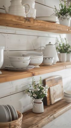 the shelves are filled with white dishes and vases on top of each other,