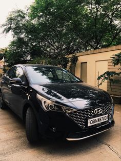 a black car is parked in front of a building with trees on the other side