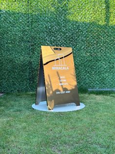 a brown paper bag sitting on top of a metal stand in front of a green hedge