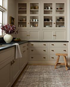 a large kitchen with white cabinets and black counter tops, along with a rug on the floor