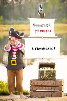 a little boy dressed up as a pirate standing in front of a sign that says, mon annversaire de petit pirate