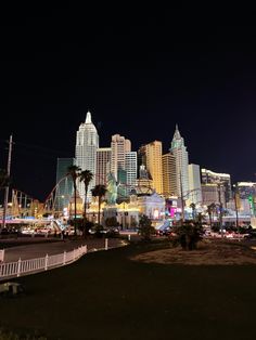 the city skyline is lit up at night with palm trees and buildings in the background