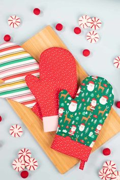 two oven mitts sitting on top of a cutting board next to candy canes