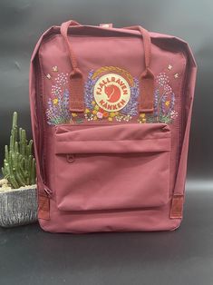 Welcome to our charming collection of hand-embroidered Fjallraven Kanken backpacks, meticulously crafted with love and precision. Elevate your style and stay organized on-the-go with these premium quality backpacks available in two convenient sizes:  - Medium (27x38x13cm)  - Large (32x42x13cm) + Key Features: - Hand-Embroidered Excellence: Each Fjallraven Kanken backpack is adorned with exquisite hand-embroidery, creating a unique and exclusive piece that sets you apart from the crowd. - Premium Casual Embroidered Backpack, School Backpack With Floral Embroidery, Custom Embroidered Backpack For Travel, Custom Embroidered Travel Backpack, Embroidered Patch Backpack For Everyday Use, Embroidered Backpack For Everyday And Back To School, Backpack Kanken, Kanken Embroidery, Kanken Classic