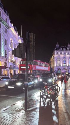 a city street at night with cars, buses and people walking on the side walk