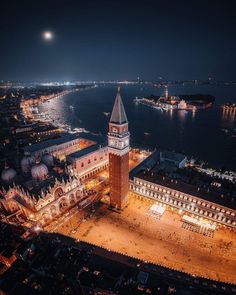 an aerial view of a city at night with the moon in the sky above it