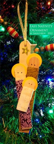 an ornament hanging from a christmas tree decorated with nativity cribs