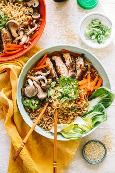 two bowls filled with noodles, meat and veggies next to chopsticks