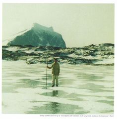 a man standing in the middle of an ice covered field holding a stick and wearing a hat