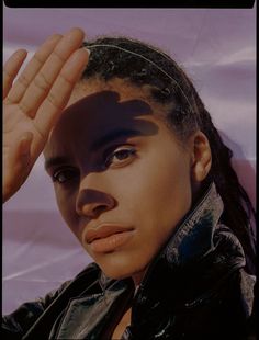 a close up of a person wearing a jacket and holding their hand on her head