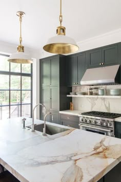 a large kitchen with marble counter tops and stainless steel appliances, along with two pendant lights hanging from the ceiling