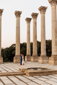 a man and woman standing in front of some pillars