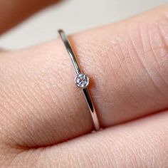 a close up of a person's hand holding a ring with a diamond on it