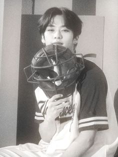 a young man wearing a catchers mask sitting on top of a bed