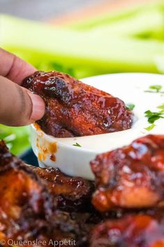 a person dipping sauce on top of chicken wings