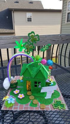 a house made out of green grass with flowers and shamrocks on the table outside