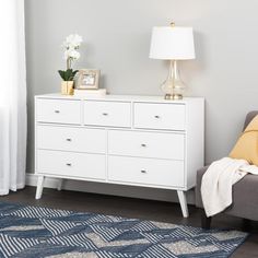 a white dresser sitting next to a bed in a bedroom