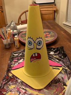 a yellow cone with an angry face on it sitting on top of a wooden table