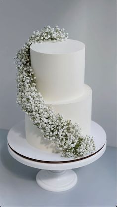 a three tiered white cake with baby's breath on top