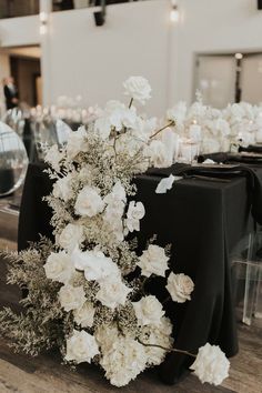 white flowers and greenery decorate the centerpieces of this black tableclothed reception