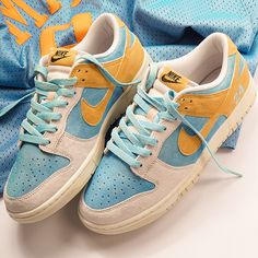 a pair of blue and yellow sneakers on top of a white surface next to a basketball jersey