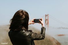 a woman taking a photo of the golden gate bridge