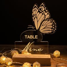 a table sign with lights around it and a butterfly sitting on top of the sign