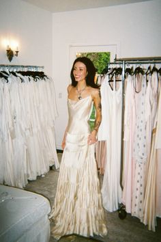 a woman standing in front of some dresses