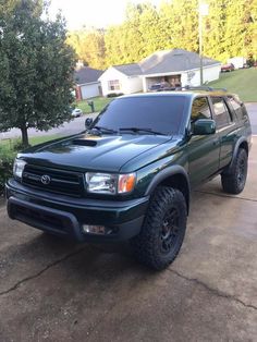 a green truck parked on top of a driveway