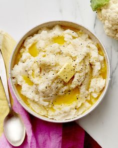 mashed potatoes with butter and seasoning in a bowl next to a pink napkin