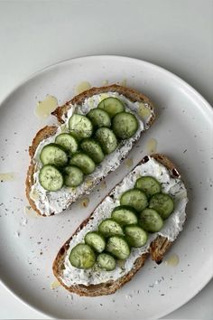 two pieces of bread with cucumbers on them are sitting on a white plate