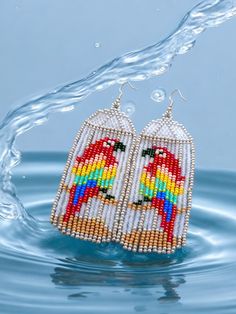 a pair of beaded bird earrings floating in water