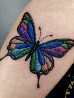 a colorful butterfly tattoo on the arm