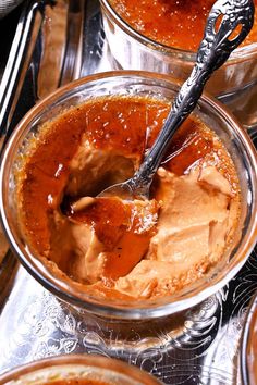 two bowls filled with peanut butter on top of a metal tray next to silver spoons