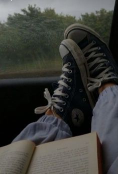 a person sitting in the back seat of a car with their feet on an open book