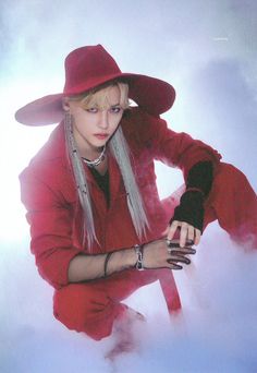 a woman in a red outfit and hat sitting on the ground with her hands behind her head