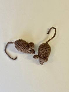 two small crocheted mice sitting next to each other on a white table top