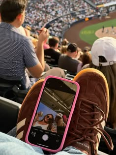 a cell phone sitting on top of a person's feet in front of a baseball field