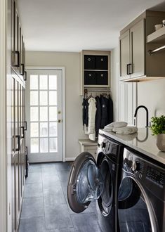 a washer and dryer are in the middle of a long hallway with cabinets