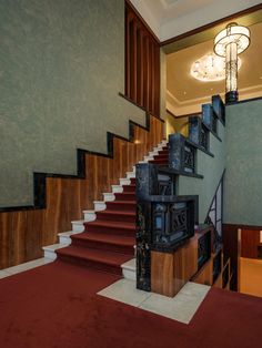 the stairs are lined with wooden boxes on top of carpeted flooring in front of a chandelier