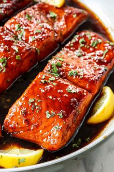 salmon in a pan with lemon wedges and parsley