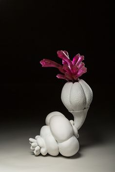 a white sculpture with pink flowers in it's head on a gray surface, against a black background